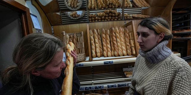 Bakery owner Florence Poirier, left, smells fresh baguette at a bakery in Versailles, west of Paris, on Nov. 29, 2022.