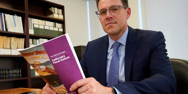Legislative analyst Gabriel Petek shows a copy of his office's analysis of the state's fiscal outlook for 2023-24, which was released Wednesday. California is likely to run a $25 billion budget deficit next year, ending a run of record surpluses.
