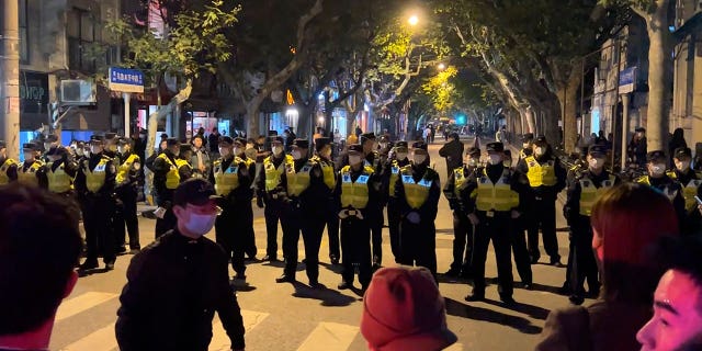 Policiais chineses bloqueiam o acesso a um local onde os manifestantes se reuniram em Xangai no domingo, 27 de novembro de 2022.