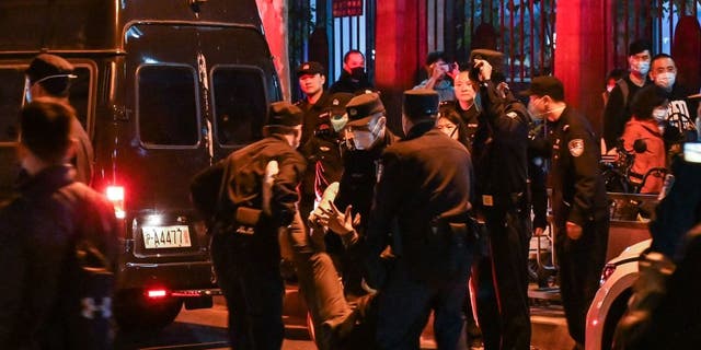 A man is arrested while people gathering on a street in Shanghai on November 27, 2022, where protests against China's "zero-COVID" policy took place the night before following a deadly fire in Urumqi, the capital of the Xinjiang region. 