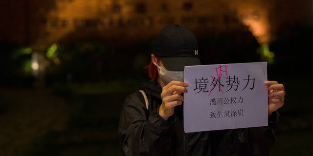 A protester holds up a paper which reads "Not foreign forces but internal forcers" and "Abuse of Government power plunge the people into misery and suffering" during a gathering at the University of Hong Kong.