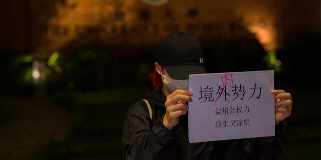 A protester holds up a paper which reads "Not foreign forces but internal forcers" and "Abuse of Government power plunge the people into misery and suffering" during a gathering at the University of Hong Kong.