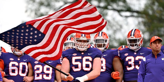 Will Putnam (56) of the Clemson Tigers holds the American flag in honor of Veterans Day during a game against the Louisville Cardinals at Memorial Stadium Nov. 12, 2022, in Clemson, S.C. 