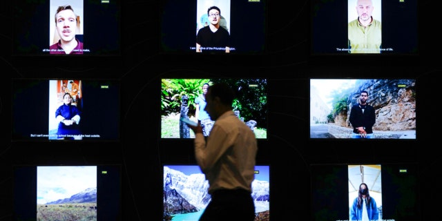 A man walks past a display of videos addressed to world leaders at the COP27 United Nations climate summit, Saturday Nov. 19, 2022, in Sharm el-Sheikh, Egypt. 