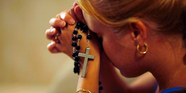Woman prays with a rosary in a church