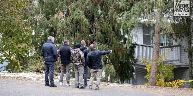 Investigators are seen searching parking lot area behind the  house in Moscow, Idaho Monday, November 21, 2022, where four people were slain on November 13.