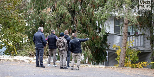 Investigators are seen searching parking lot area behind the  house in Moscow, Idaho Monday, November 21, 2022, where four people were slain on November 13.