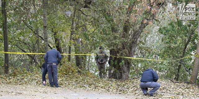 Investigators are seen searching a parking lot area behind the house in Moscow, Idaho Monday, November 21, 2022, where four people were slain on November 13.