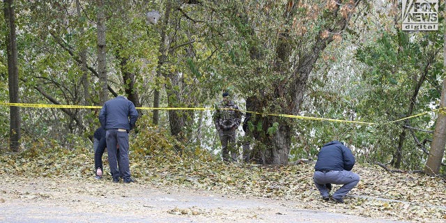 Investigators are seen searching a parking lot area behind the house in Moscow, Idaho Monday, November 21, 2022, where four people were slain on November 13.