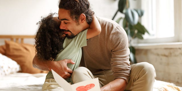 Father hugging his child and holding an homemade card
