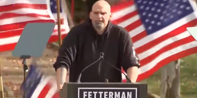 American flags topple behind Democratic U.S. Senate candidate John Fetterman as he speaks to rallygoers in Pennsylvania.