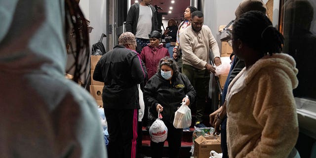 Maria Correa, center, who says she is sick with cancer and cannot work, accepts a turkey and Thanksgiving trimmings during a Thanksgiving food giveaway on Nov. 22, 2022, in Washington.