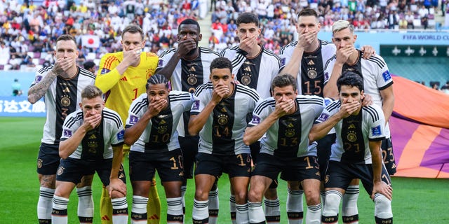 German players cover their mouths in protest as they pose for a team photo. Back row (L-R): David Raum, Manuel Neuer, Antonio Ruediger, Niklas Sule, Nico Schlotterbeck. Front row (L-R): Joshua Kimmich, Serge Gnabry, Jamal Musiala, Thomas Mueller, Ilkay Guendogan. The players posed before a FIFA World Cup Qatar 2022 Group E match between Germany and Japan at Khalifa International Stadium Nov. 23, 2022, in Doha, Qatar.