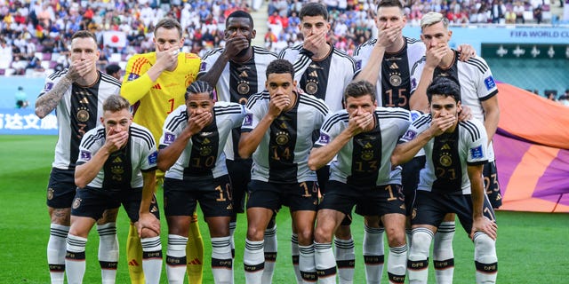 German players cover their mouths in protest as they pose for a team photo. Back row (L-R): David Raum, Manuel Neuer, Antonio Ruediger, Niklas Sule, Nico Schlotterbeck. Front row (L-R): Joshua Kimmich, Serge Gnabry, Jamal Musiala, Thomas Mueller, Ilkay Guendogan. The players posed before a FIFA World Cup Qatar 2022 Group E match between Germany and Japan at Khalifa International Stadium Nov. 23, 2022, in Doha, Qatar.