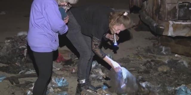 Gretchen Pace and Kimberly Williams look through debris from a fire that destroyed a neighbor's van. The pair found thousands of dollars and returned it to the neighbor.