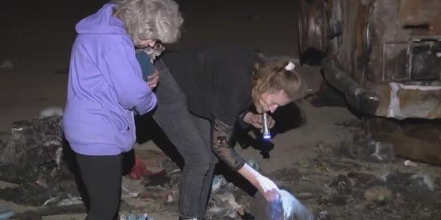 Gretchen Pace and Kimberly Williams look through debris from a fire that destroyed a neighbor's van. The pair found thousands of dollars and returned it to the neighbor.