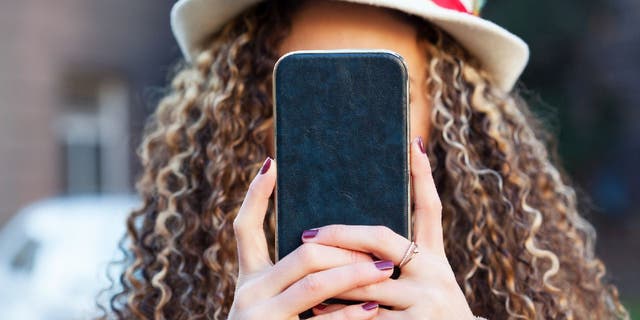 Curly haired woman holds up phone