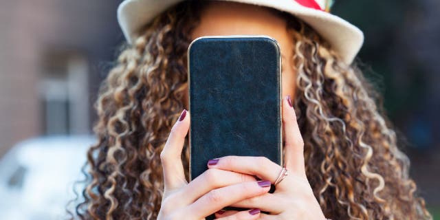 Curly haired woman holds up phone