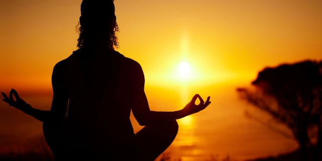 Woman meditates at sunset