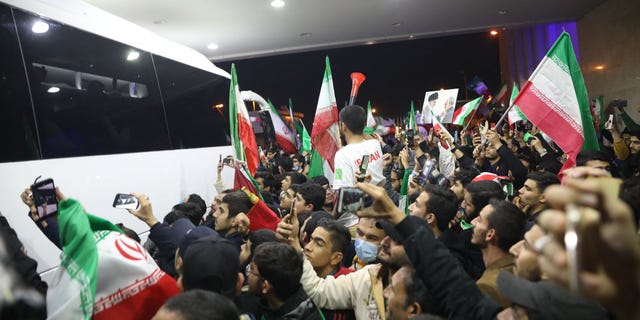 Partidarios iraníes ondean banderas mientras se reúnen en el aeropuerto Imam Khomeini en Teherán el 1 de diciembre de 2022 para saludar a la selección iraní a su regreso de participar en la Copa Mundial Qatar 2022. 