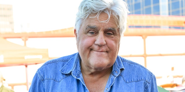 Jay Leno smiles while wearing a blue denim shirt