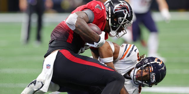 Kyle Pitts #8 of the Atlanta Falcons stiff arms Kyler Gordon #6 of the Chicago Bears following his reception during the second quarter at Mercedes-Benz Stadium on November 20, 2022 in Atlanta, Georgia.