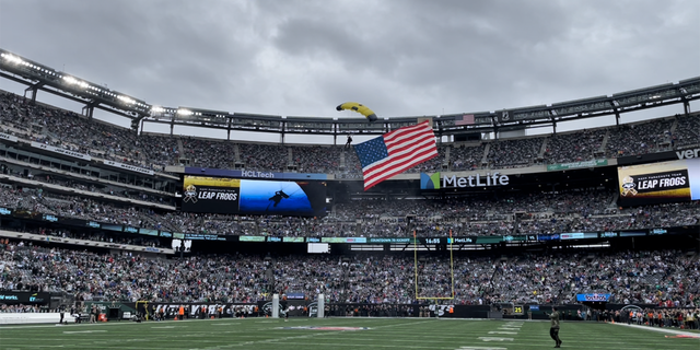 A U.S. Navy Leap Frog enters into MetLife Stadium via parachute with the American flag behind him on Nov. 6, 2022.