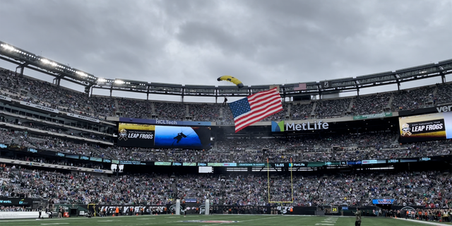 A U.S. Navy Leap Frog enters into MetLife Stadium via parachute with the American flag behind him on Nov. 6, 2022.