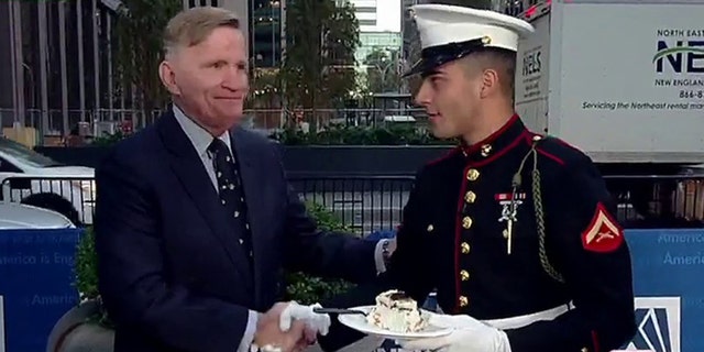 Ret. Lt. Col. Art Gorman (left) passes a slice of cake to the youngest Marine during the Marine Corps' honorary cake-cutting tradition on Fox Square in midtown Manhattan on Nov. 10, 2022.