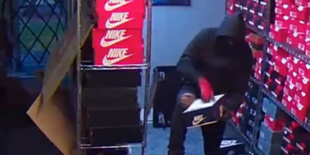 A robber wearing red gloves digs into a shoe box only to discover it has only one shoe.