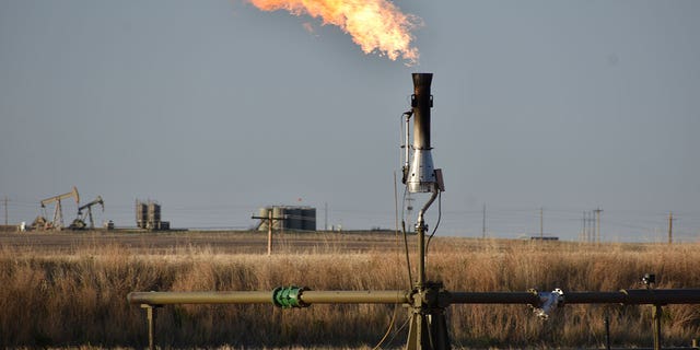 A flare for burning excess methane from crude oil production is seen at a well pad in North Dakota on May 18, 2021.