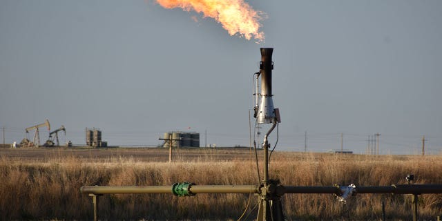 A flare for burning excess methane from crude oil production is seen at a well pad in North Dakota on May 18, 2021.