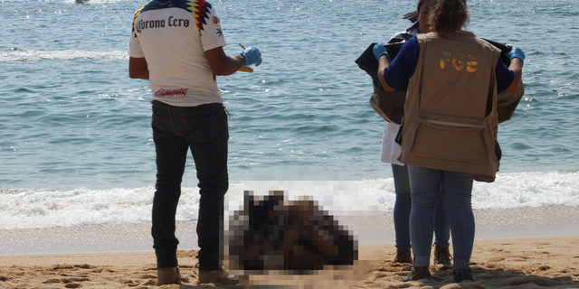 Forensic technicians work around one of the three bodies that washed up on Icacos beach in Acapulco, Mexico on November 12, 2022.