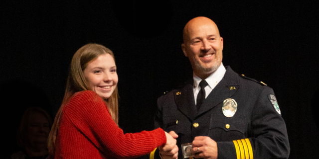 Excelsior Springs Police Chief Gregory Dull presents award to teenager Ava Donegan. 