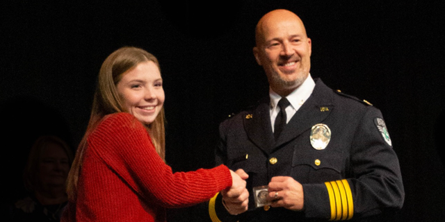 Excelsior Springs Police Chief Gregory Dull presents award to teenager Ava Donegan. 