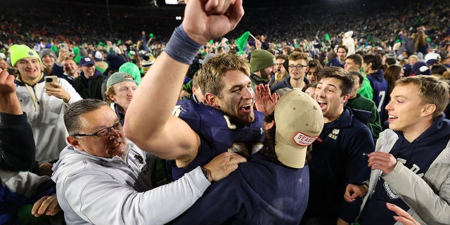 Michael Mayer #87 of the Notre Dame Fighting Irish celebrates with fans who stormed the field after defeating the Clemson Tigers 35-14 at Notre Dame Stadium on November 05, 2022 in South Bend, Indiana.