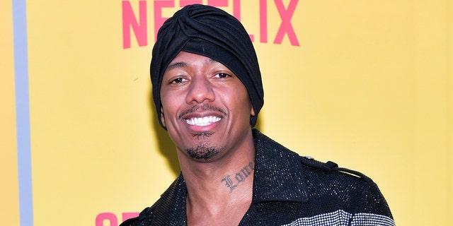 Nick Cannon smiles for a photo at a red carpet event.