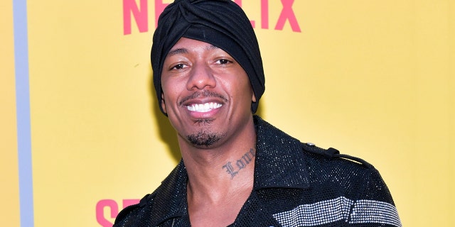 Nick Cannon smiles for a photo at a red carpet event.