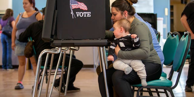 Miranda Padilla holds her 11-month-old son Grayson Sanchez while voting at a polling center in the South Valley area of Albuquerque, New Mexico, on Nov. 8, 2022.