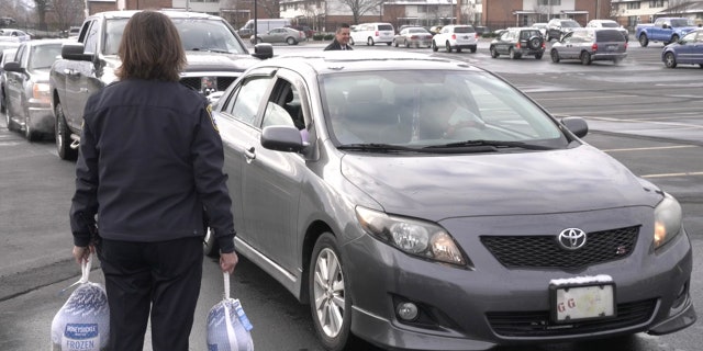 A Jackson officer waits to gift a turkey to the next resident as a part of the city's turkey giveaway.