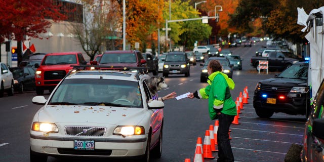 A poll worker in Salem, Ore., accepts a voter's ballot. Oregon hosts one of the most competitive gubernatorial races of the 2022 cycle.