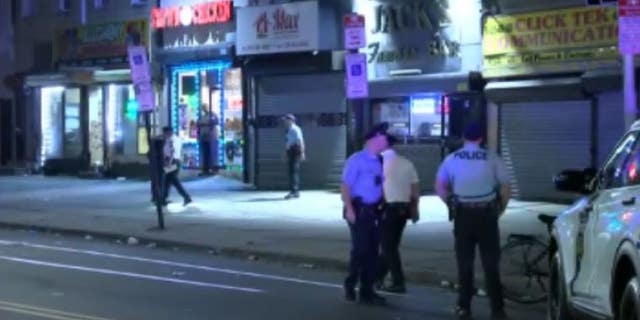 Philadelphia police officers stand outside businesses following a mass shooting outside a bar in the Kensington neighborhood.  