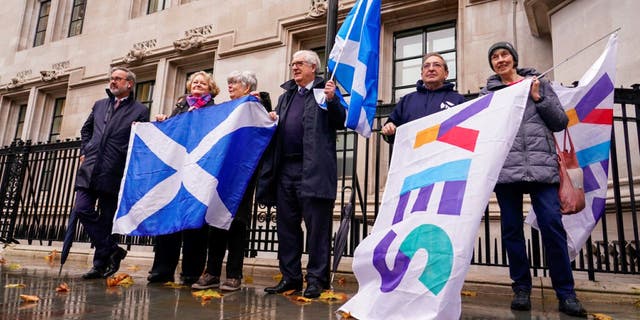 Scottish flags are held by demonstrators, outside the Supreme Court, in London, Wednesday, Nov. 23, 2022. British leaders on Monday blocked a Scottish law that would have made it easier to change one's legal gender.