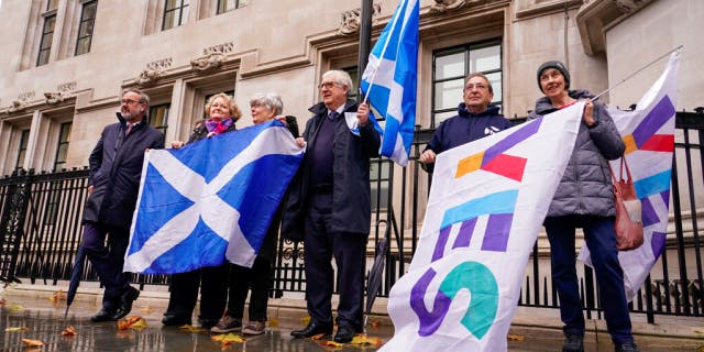 Scottish flags are held by demonstrators outside the Supreme Court in London, Wednesday, Nov. 23, 2022. 