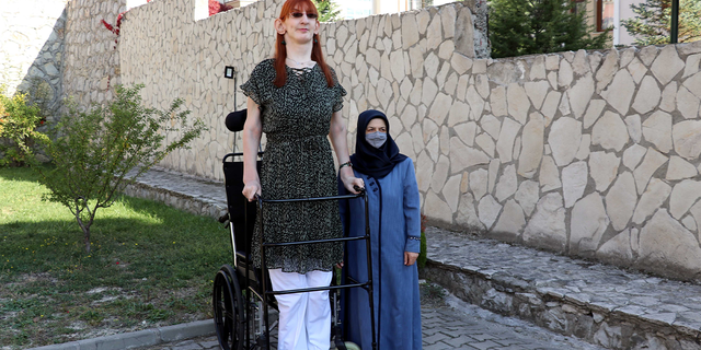 Turkish woman Rumeysa Gelgi (L), who stands 215.16 centimeters (7 feet, 0.7 inches) tall and has been confirmed as the world's tallest living woman by Guinness World Records, is seen in front of her house in Safranbolu district of Karabuk, Turkey on October 14, 2021. Gelgi's phenomenal height is due to a condition called Weaver syndrome, which causes accelerated growth and other abnormalities, Guinness World Records said in a statement. (Photo by Orhan Kuzu/Anadolu Agency via Getty Images)
