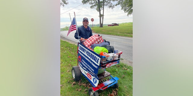 Twenty-four-year-old Tommy Pasquale poses with his new cart — after the first cart broke — filled with essentials for his walk across the U.S. on day six of the trip in Pennsylvania.