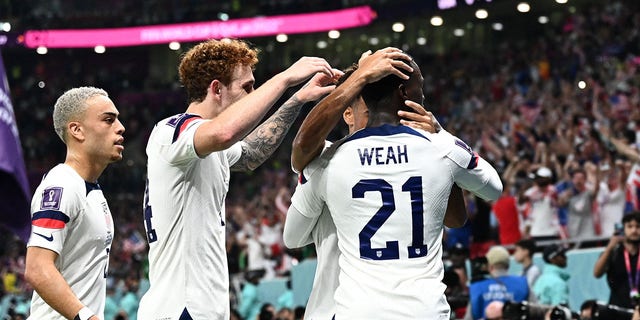 USA forward Timothy Weah, #21, celebrates with teammates after scoring his team's first goal during the Qatar 2022 World Cup Group B soccer match between the USA and Wales at the Ahmad Bin Ali Stadium in Al-Rayyan, west of Doha on November 21.  2022.