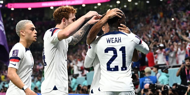 USA forward Timothy Weah, #21, celebrates with teammates after scoring his team's first goal during the Qatar 2022 World Cup Group B football match between the USA and Wales at the Ahmad Bin Ali Stadium in Al-Rayyan, west of Doha on November 21, 2022.