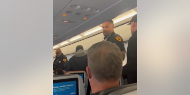 Police board a JetBlue plane after landing at Salt Lake City International Airport to arrest a man accused of holding a blade to a woman's throat midflight. 