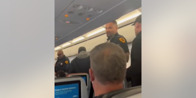 Police board a JetBlue plane after landing at Salt Lake City International Airport to arrest a man accused of holding a blade to a woman's throat midflight.